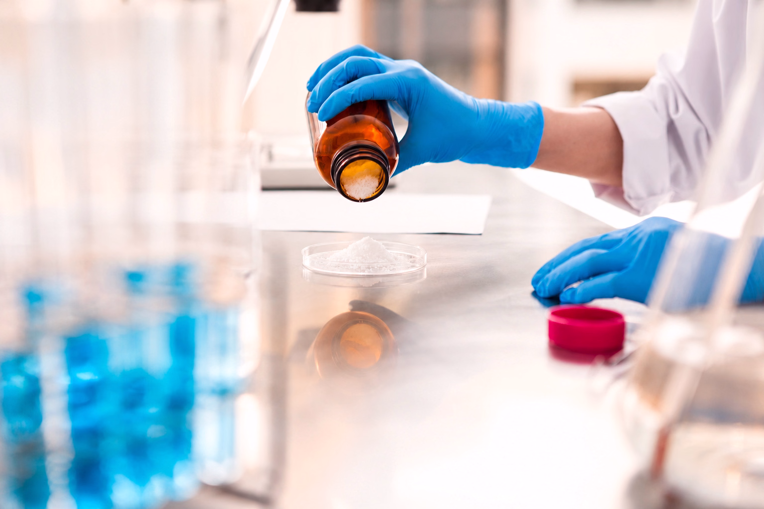 Laboratory technician performing analyses on powders using a molded glass bottle.